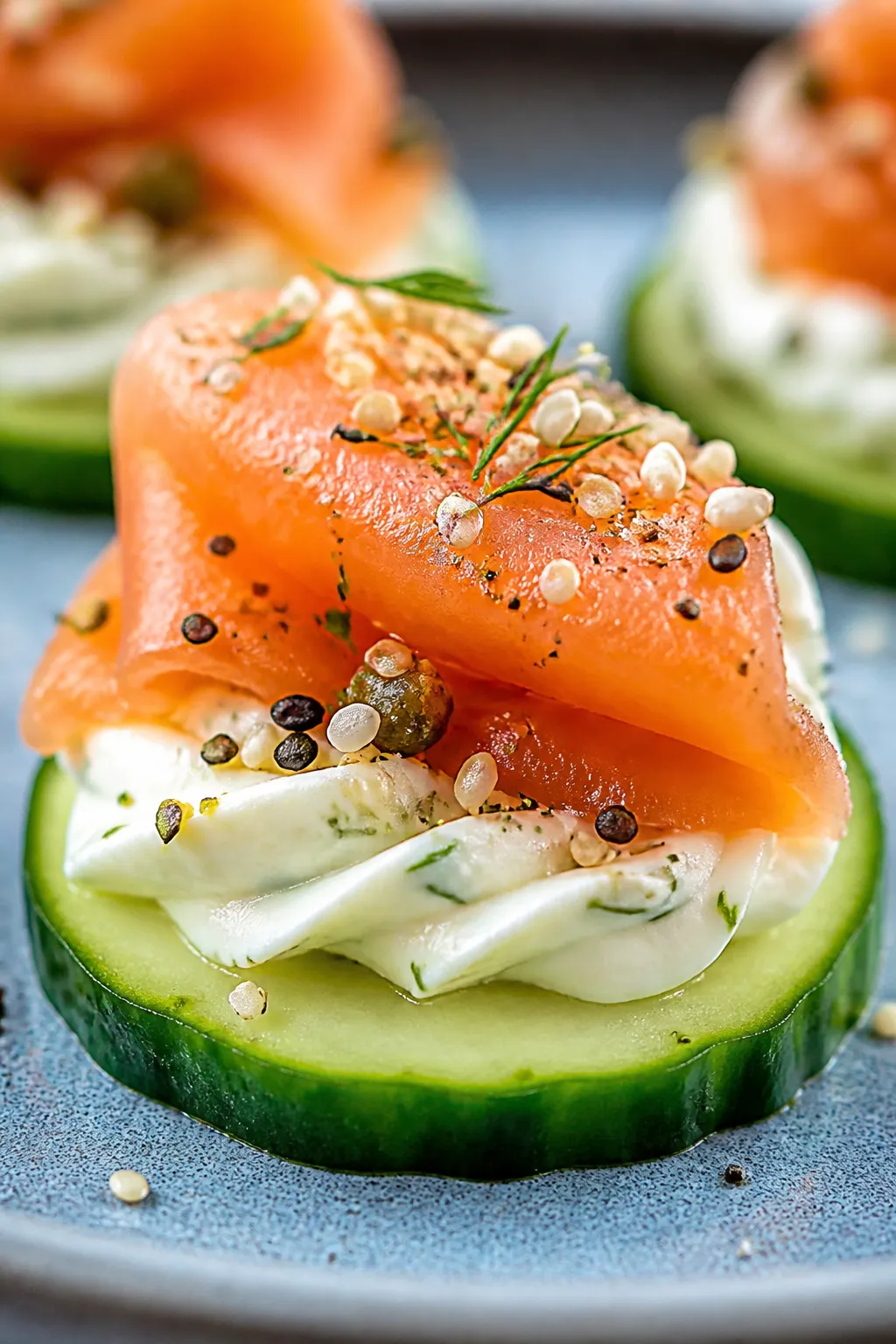 Close-up detail: A finished cucumber round topped with a swirl of lemon-dill cream cheese and a silk