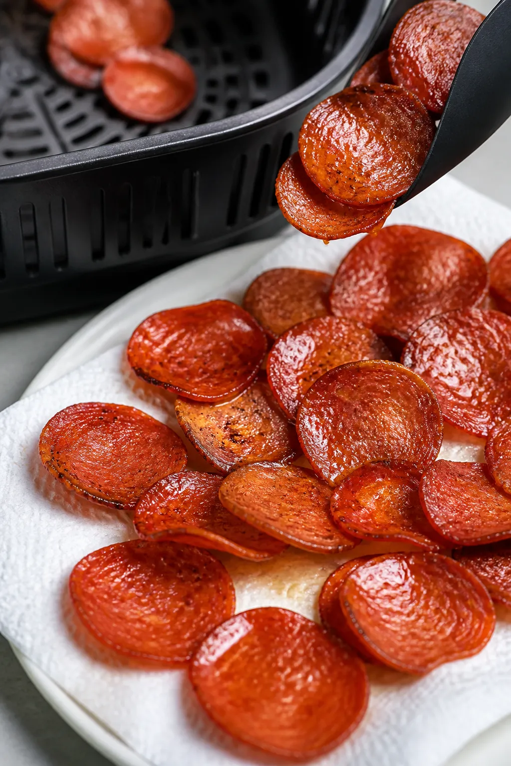 Close-up detail of freshly air-fried pepperoni crisps just out of the basket, edges curled and deepl