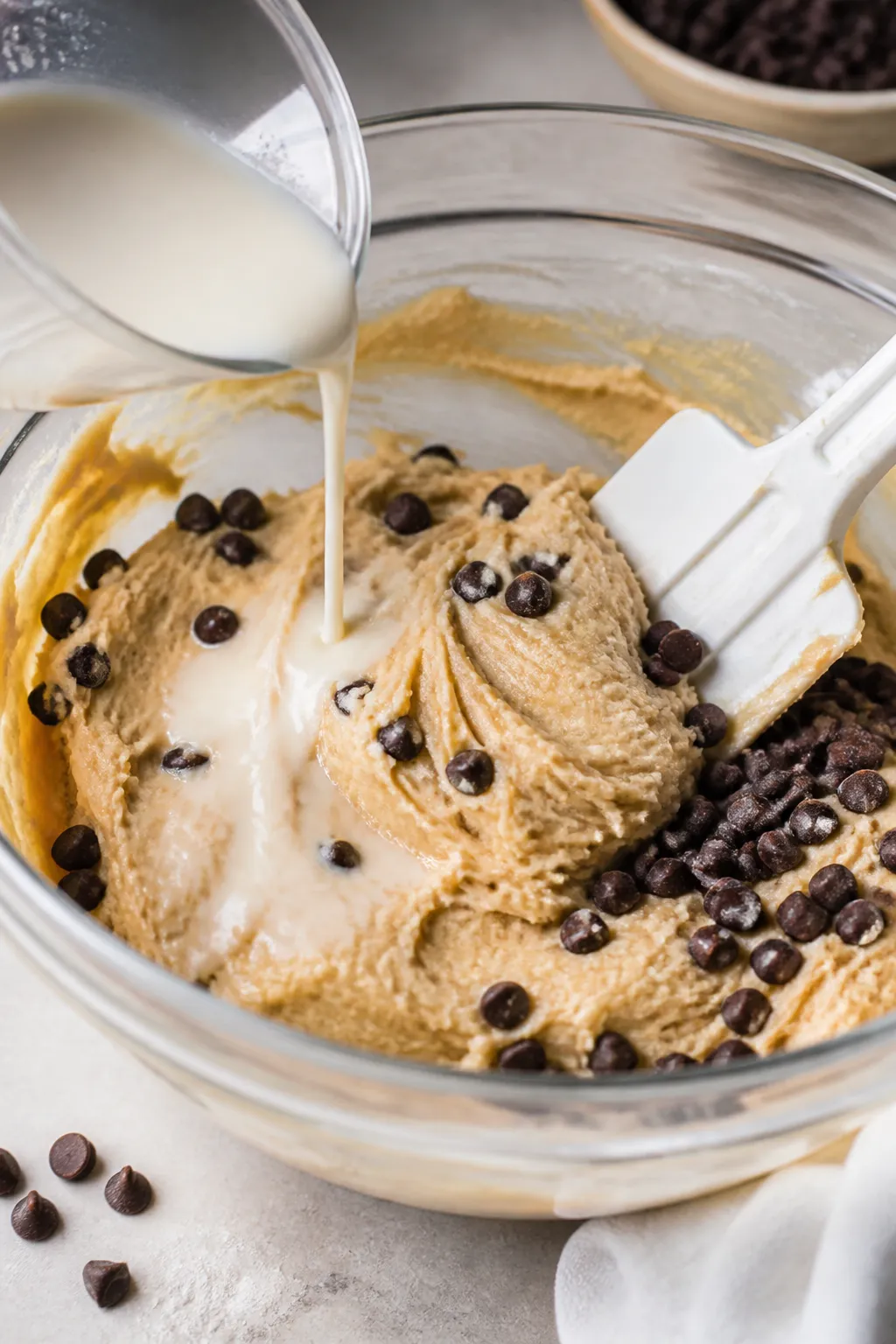 Cooking process: The dough being folded together in a glass mixing bowl, captured mid-stir as almond