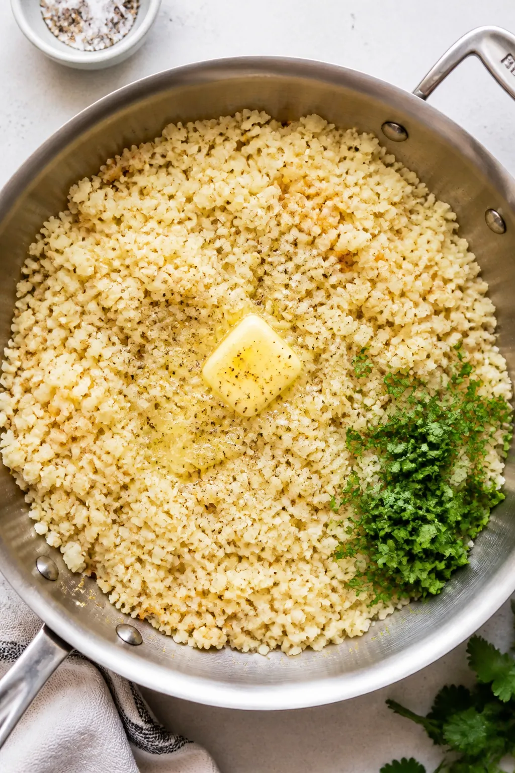 Tasty top view: Overhead shot of fluffy sautéed cauliflower rice in a wide stainless skillet, cooke